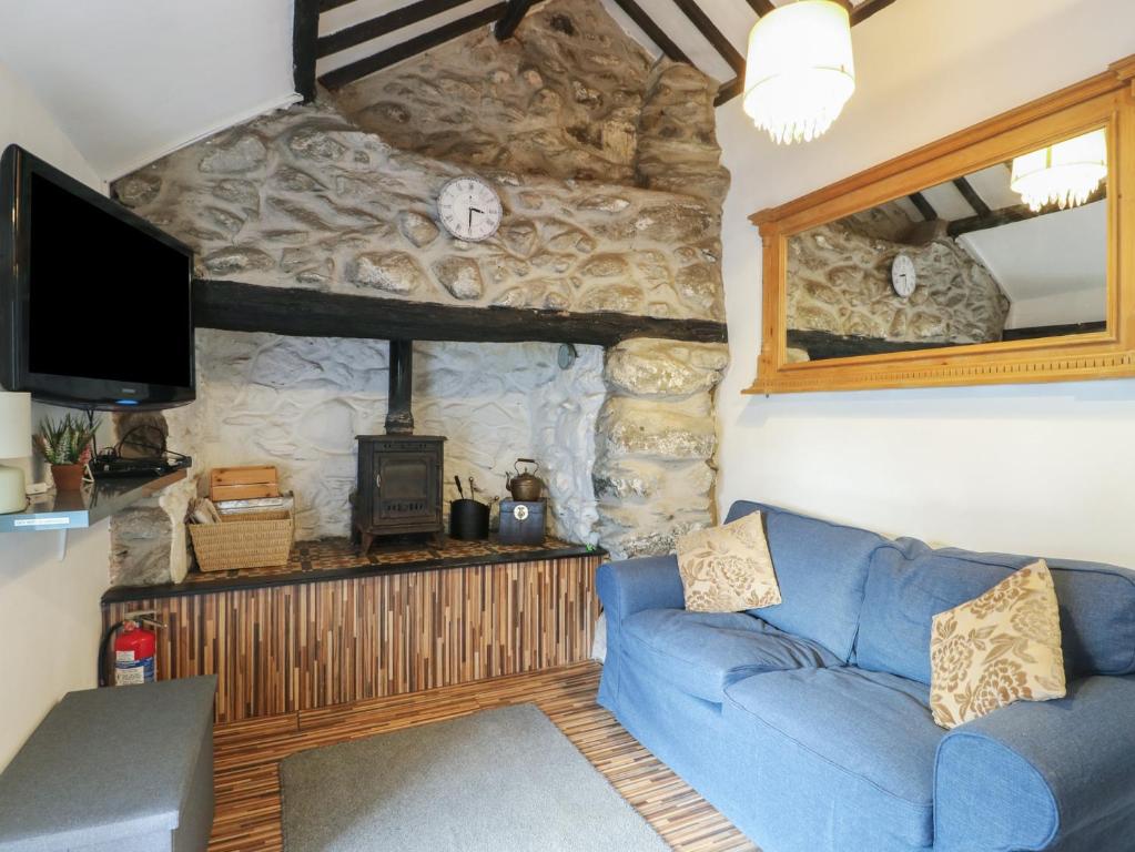 a living room with a blue couch and a tv at Fullers Studio in Holyhead