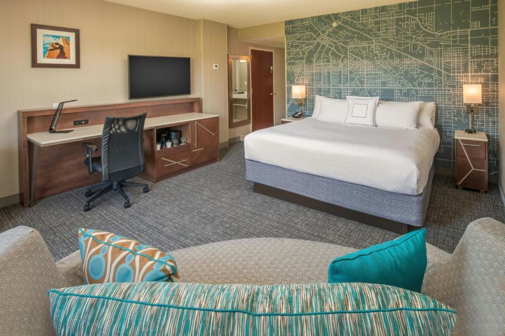 a hotel room with a bed and a desk with a computer at Courtyard Seattle Sea-Tac Area in Tukwila
