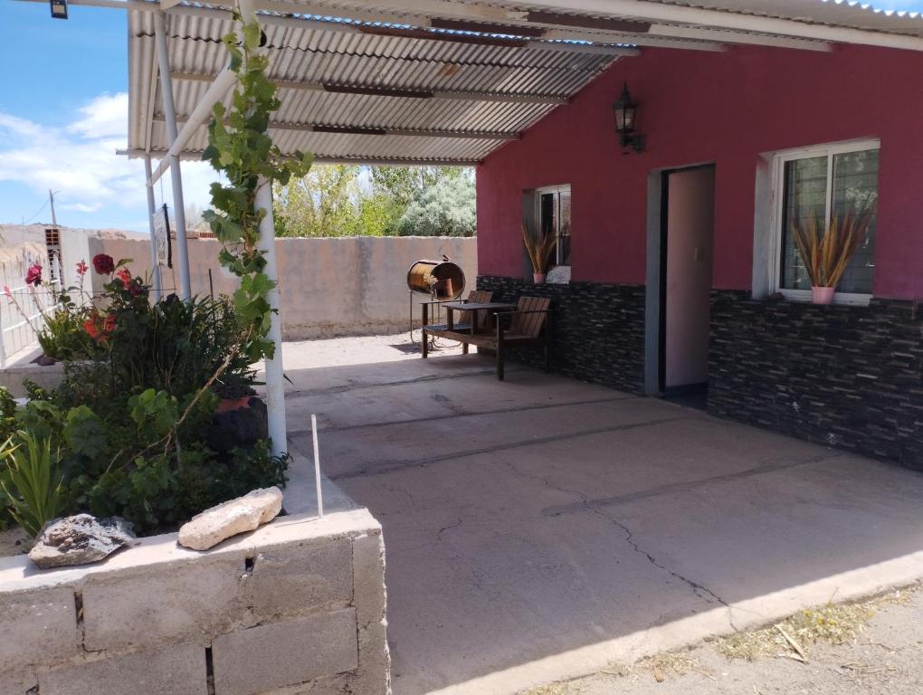 a patio with a table and a red house at Rincones de la Puna in Antofagasta de la Sierra