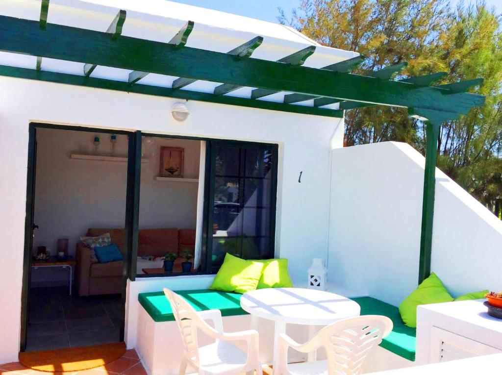 um pátio com uma mesa e cadeiras e uma pérgola em Casita Blanca, Jardín del Sol 1 em Playa Blanca