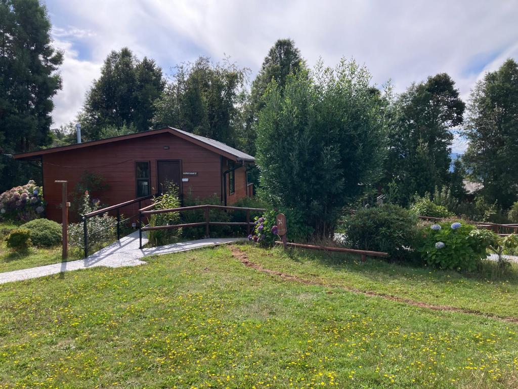 a small house in a field next to a yard at Cabañas Kalfvgen in Valdivia
