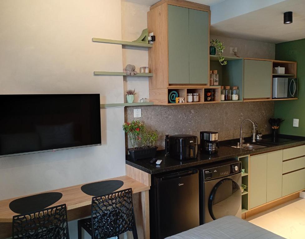 a kitchen with a table and a tv and a counter at Studio Centro Curitiba in Curitiba