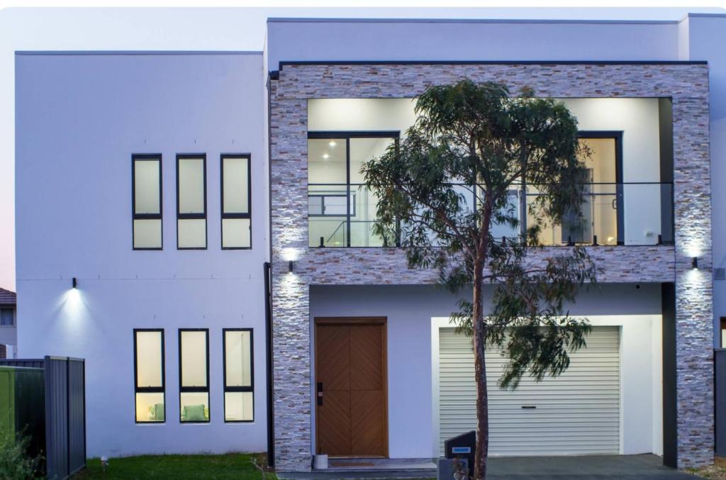 a white house with a door and a tree at Brand New Elegant House in Marsden Park