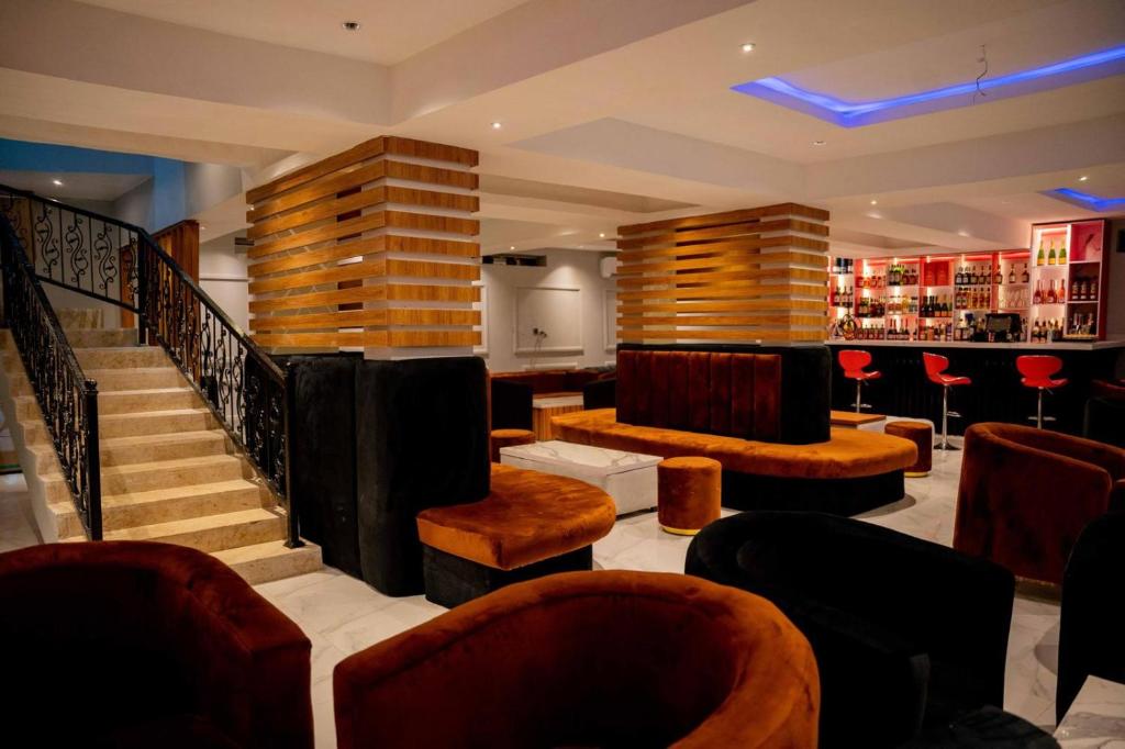 a lobby with chairs and a staircase and a bar at Nirvana City Hotel in Benin City