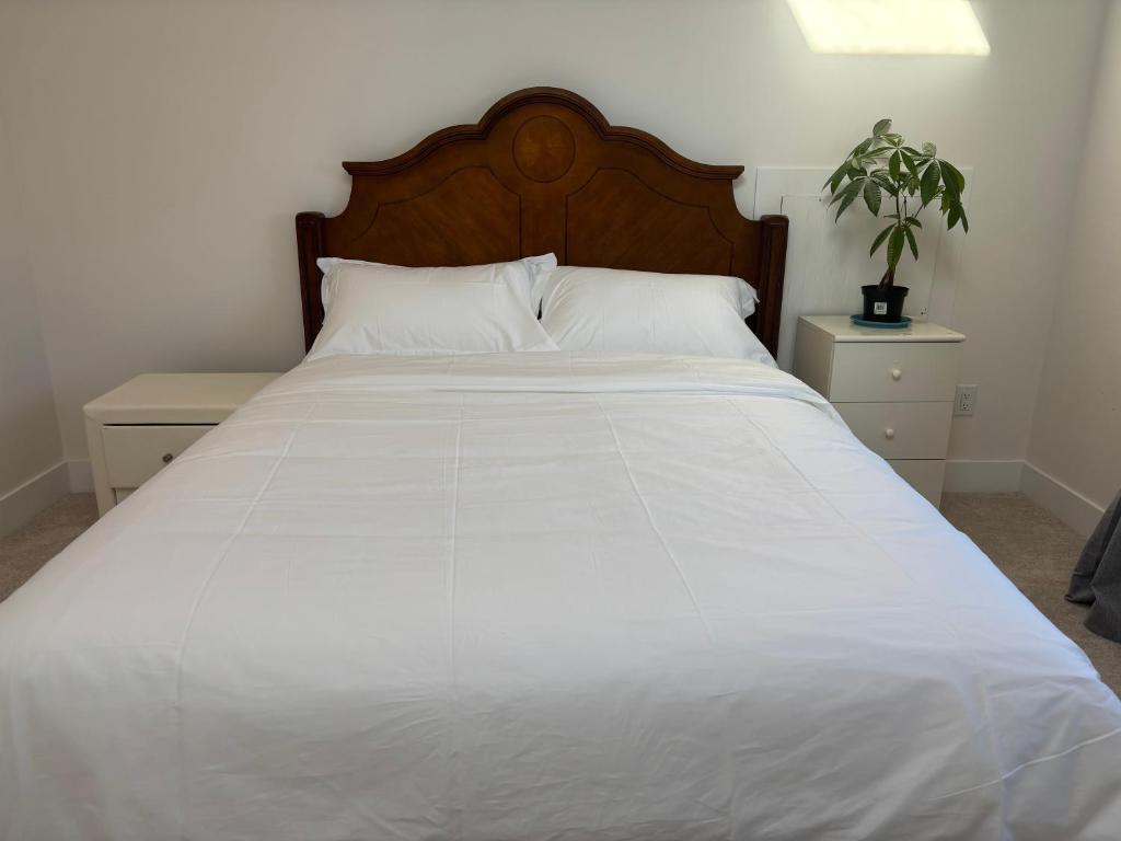 a white bed with a wooden headboard and white sheets at Comfortable Private Room in a Shared Home in Richmond