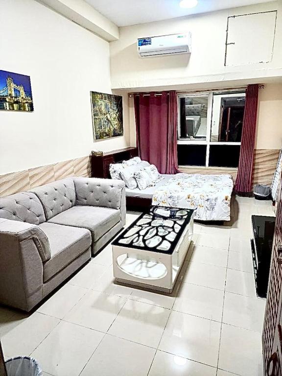 a living room with a couch and a bed at Ajman Downtown Central AISOOGA in Ajman 