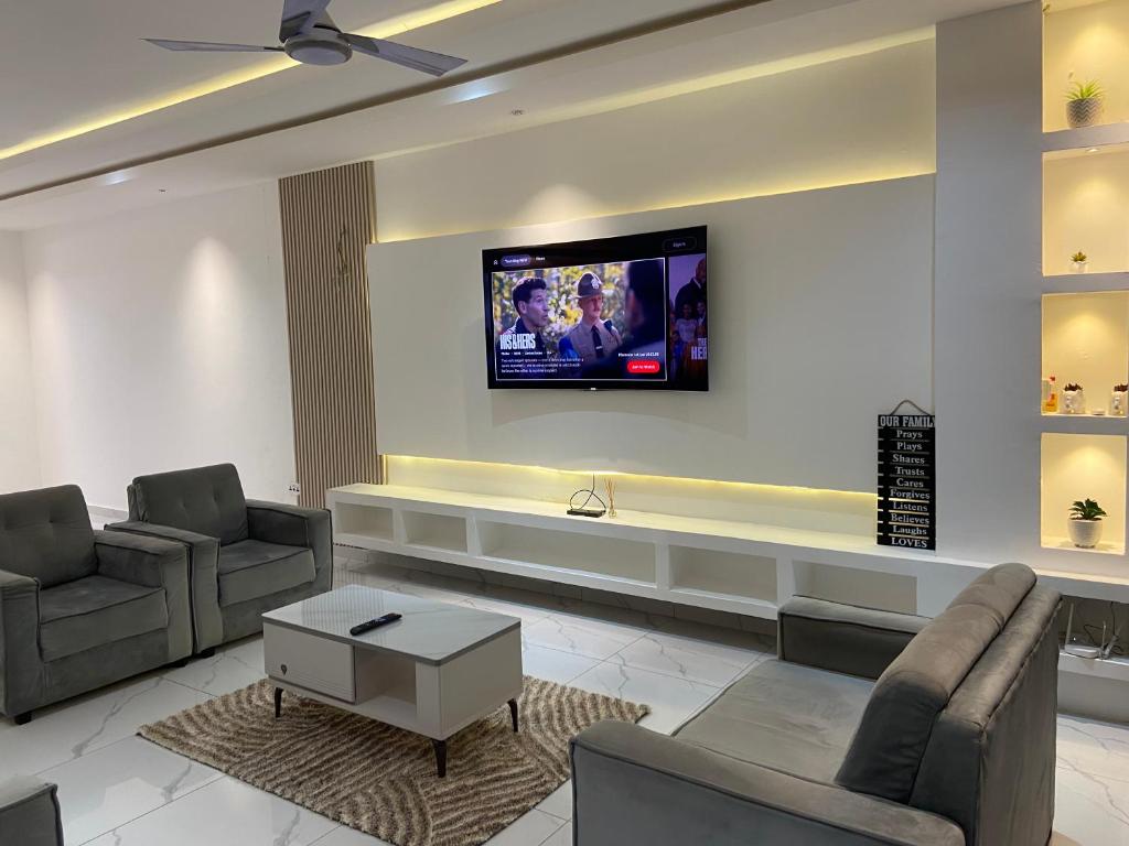 a living room with two chairs and a tv on a wall at 1BR Ultra Modern Apartment in Gbawe in Gbawe