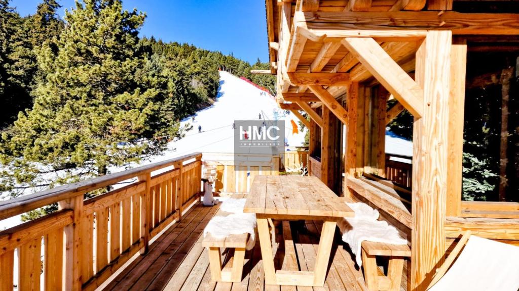 a wooden deck with a picnic table and a hiking sign at Ski Bob accès direct pistes jacuzzi privé in Bolquere Pyrenees 2000