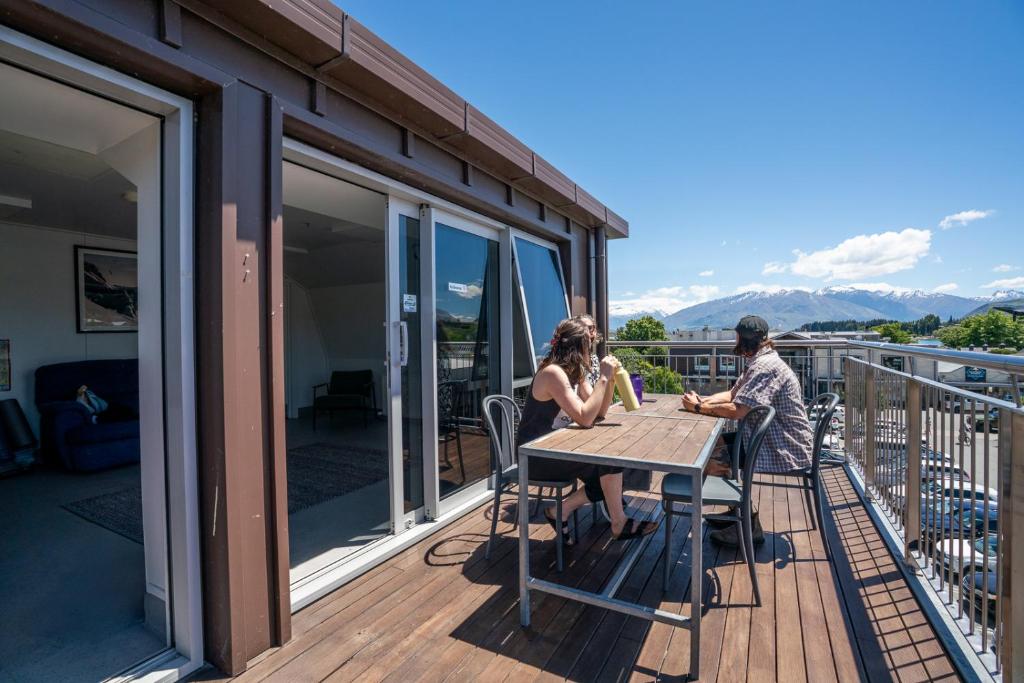 two people sitting at a table on the deck of a house at The Brownston Hostel in Wanaka