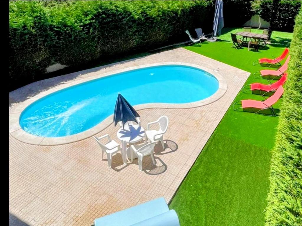 a swimming pool with chairs and an umbrella and an umbrella at Vivenda Do Relaxo '' Relax Villa " in Freiria