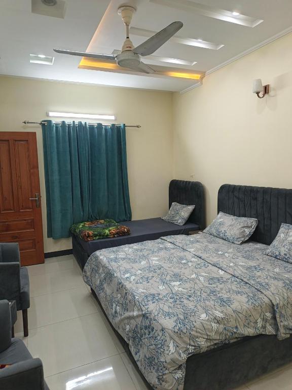 ein Schlafzimmer mit zwei Betten und einem Deckenventilator in der Unterkunft IsLodge in Islamabad