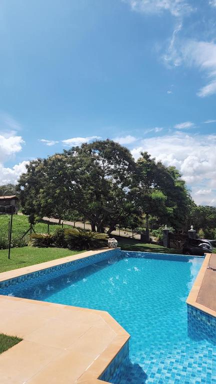 Ein blauer Swimmingpool mit einem Baum im Hintergrund in der Unterkunft Refúgio Ibiúna in Ibiúna