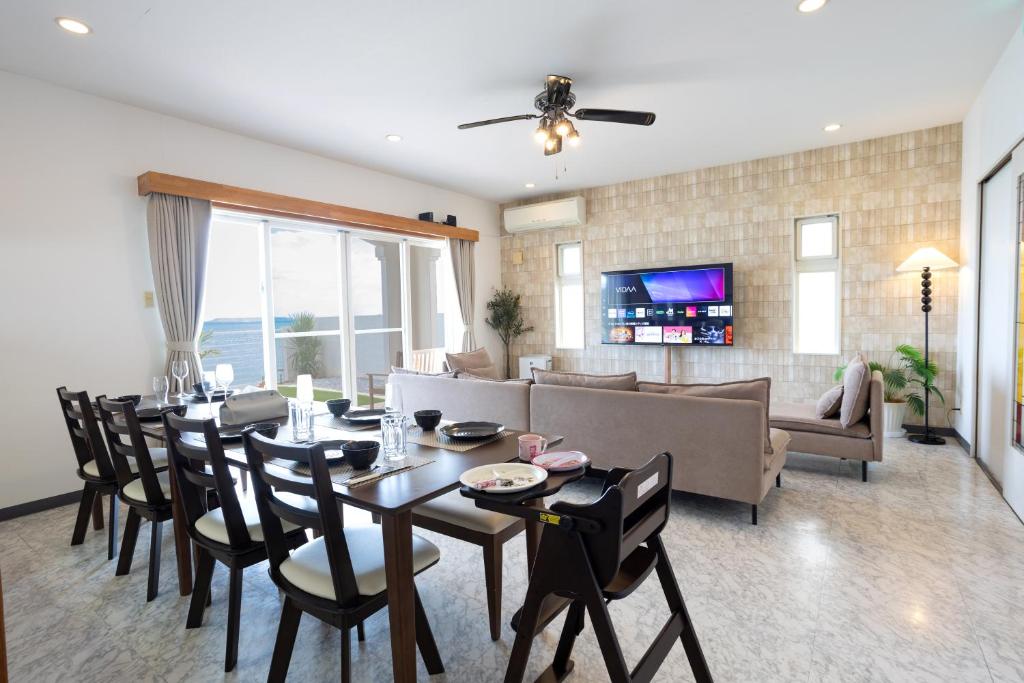 a dining room and living room with a table and chairs at Ocean Terrace金武 in Kin
