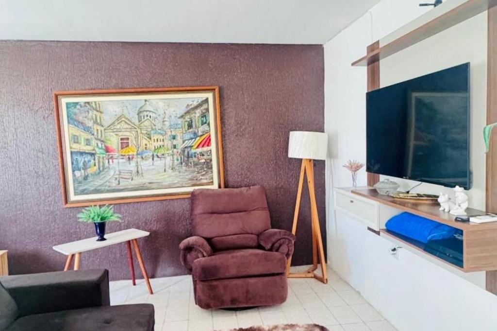 a living room with a chair and a television at Casa com 3 quartos carnaval Olinda in Olinda
