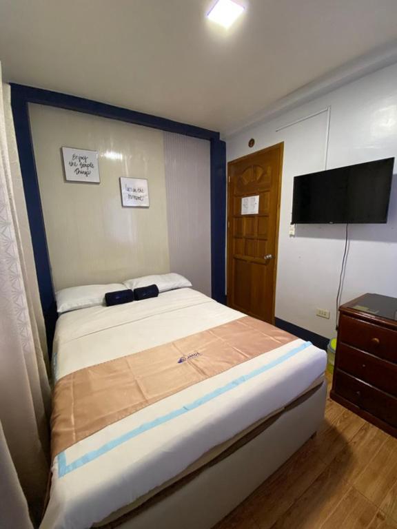 a bedroom with a large bed and a flat screen tv at JMCL RESIDENCES in Tacloban