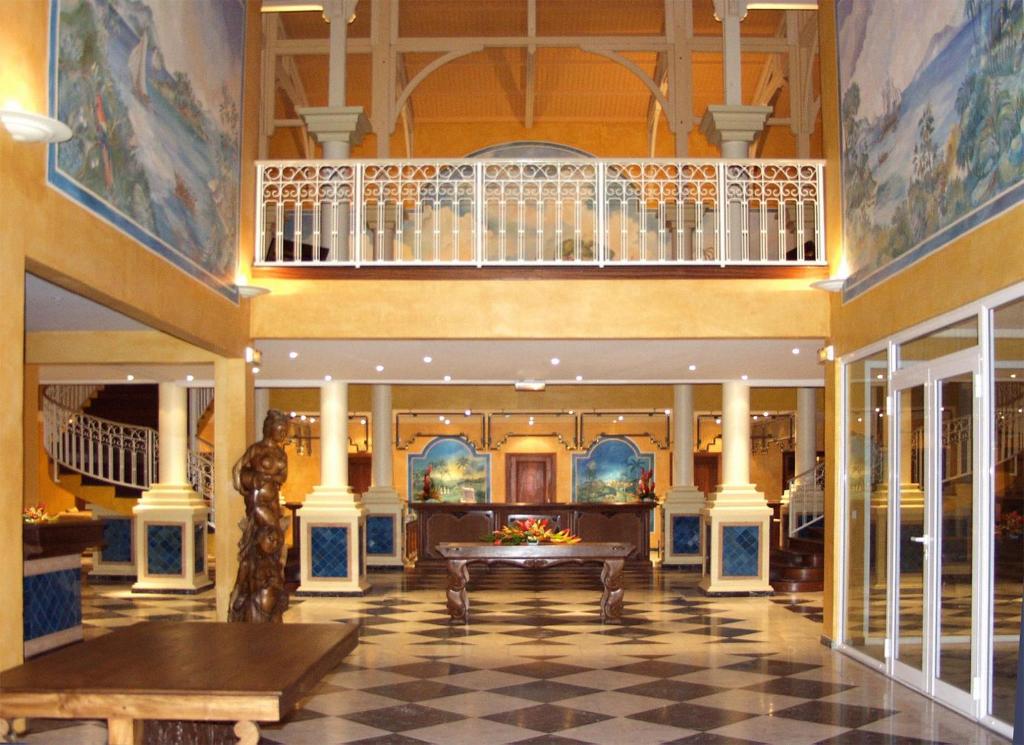 a lobby of a hotel with a staircase and a table at Appartement à la Résidence LA PLANTATION RESORT and SPA in Saint-François