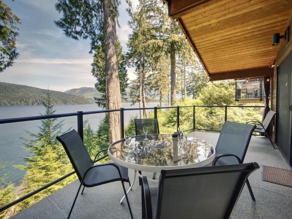 a patio with a table and chairs and a view of a lake at Oceanfront view 2 entertainment areas -Pet Friendly in Port Renfrew