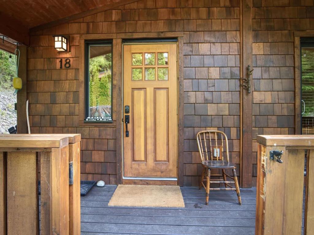 a front door of a wooden house with a chair at The Rocky Knoll - Garden View - Pet Friendly in Port Renfrew