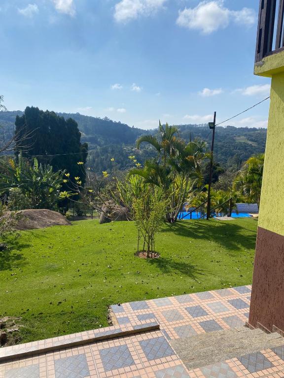 a view of a field of grass with a house at Sítio encantador com piscina e lazer completo in São Roque