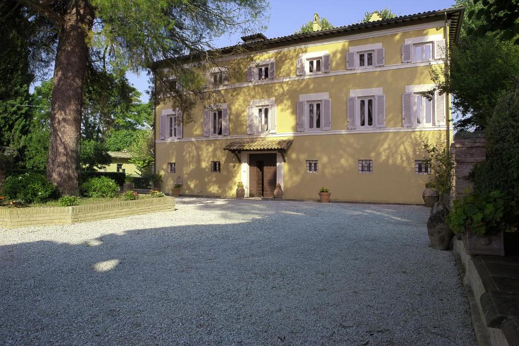 un gran edificio amarillo con un árbol y una entrada en Villa Pandolfi Elmi, en Spello