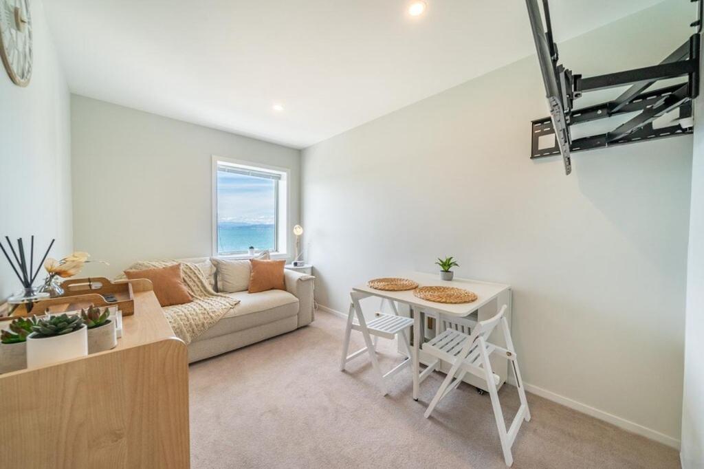 a living room with a couch and a table at Luxury Beachfront Apartment - Private Upper Suite in Wellington