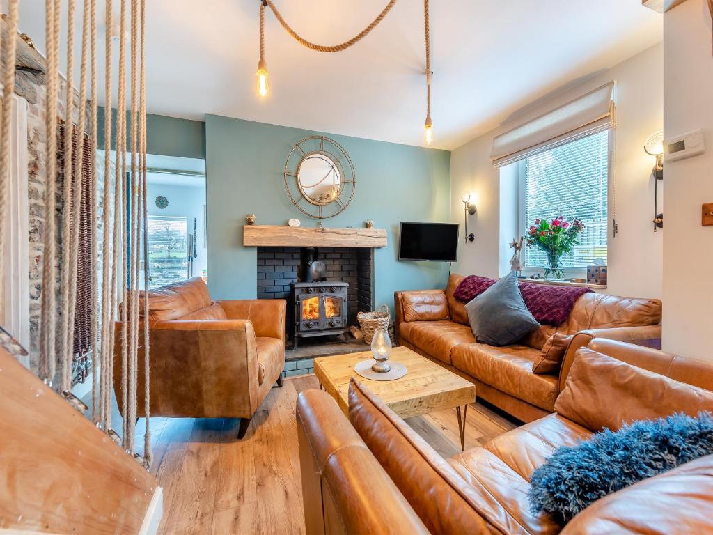 a living room with leather furniture and a fireplace at Oystercatcher Cottage in Haverfordwest