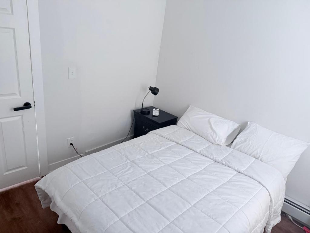 a bedroom with a white bed with a night stand at Cozy single room in Fall River