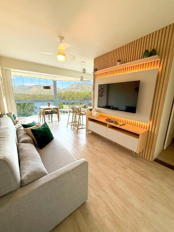 a living room with a couch and a flat screen tv at Encanto da Praia LUXO Ap 2 qts Pe na Areia Camboinhas in Niterói
