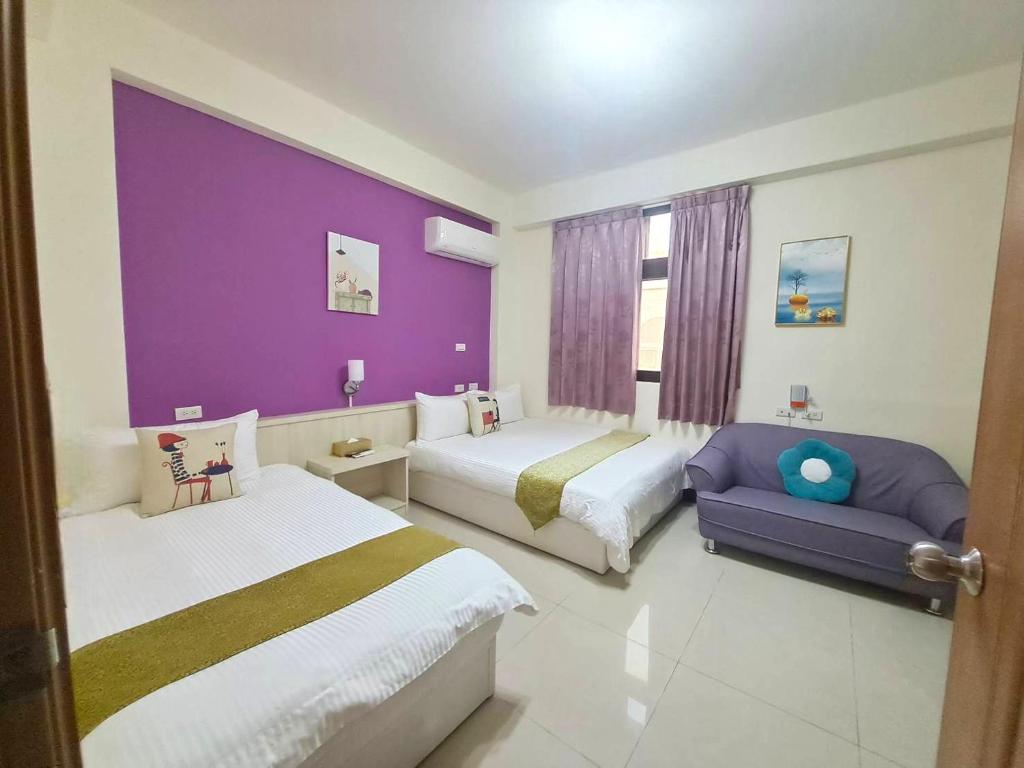 a bedroom with two beds and a purple wall at 小蘋果民宿 in Jinning