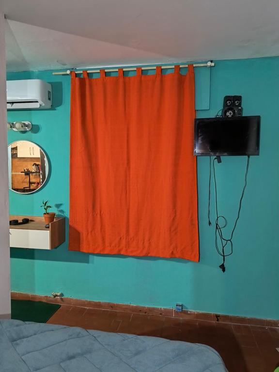 a bedroom with an orange curtain on a blue wall at San Martin 40 in Villa Carlos Paz