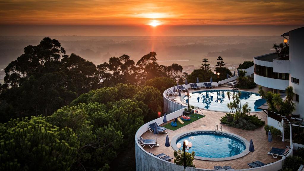 a view of a hotel with two pools and a sunset at Sao Felix Hotel Hillside & Nature in Póvoa de Varzim