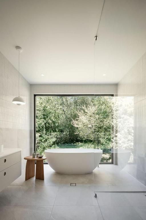 a large bath tub in a bathroom with a large window at Treetop House in Crafers
