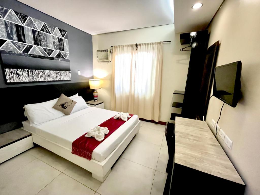 a bedroom with a white bed with a red blanket at D'Goldwin Lodge in Coron
