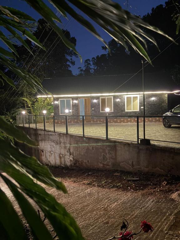 a house with lights on a tennis court at night at Florence Stays Munnar in Munnar