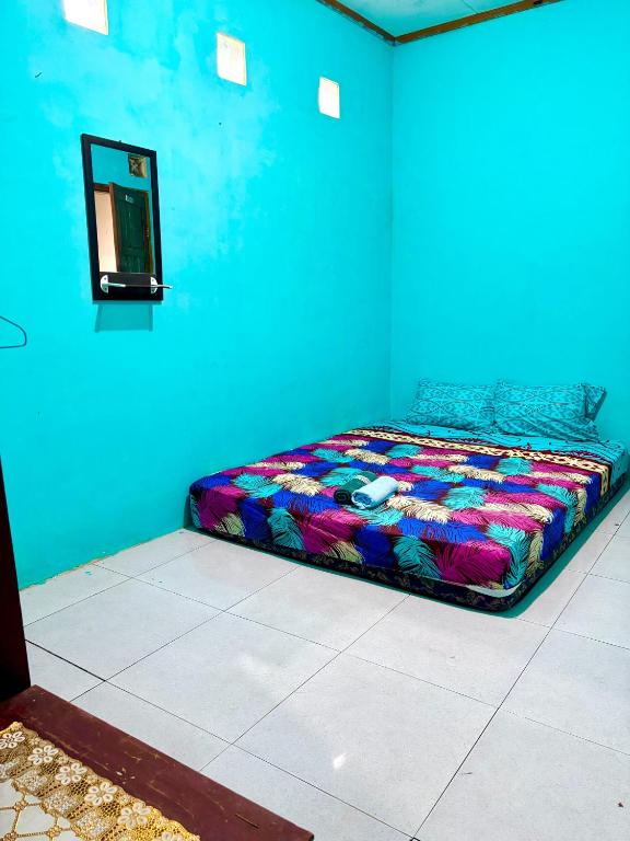 a bedroom with a colorful bed in a blue room at Kopinka in Yogyakarta