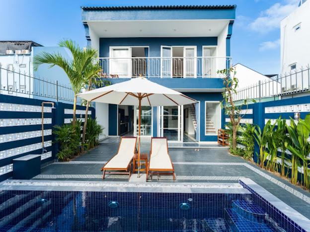 a house with two chairs and an umbrella next to a swimming pool at Shadyside 4B in Tân Thành (1)