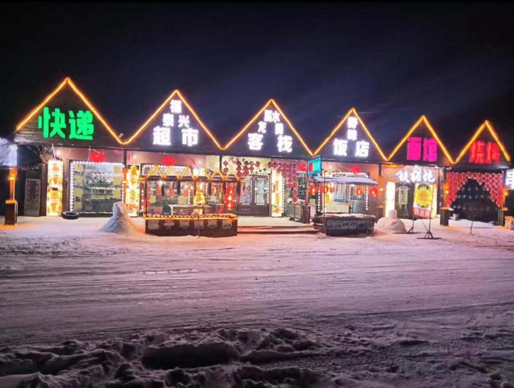 a building with christmas lights on it in the snow at Snow Valley Xishui Dragon Soaring Inn in Wuchang