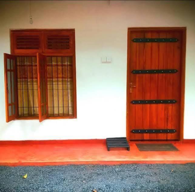 two wooden doors on a white wall with a mat in front at Sahan geust inn in Wellawaya