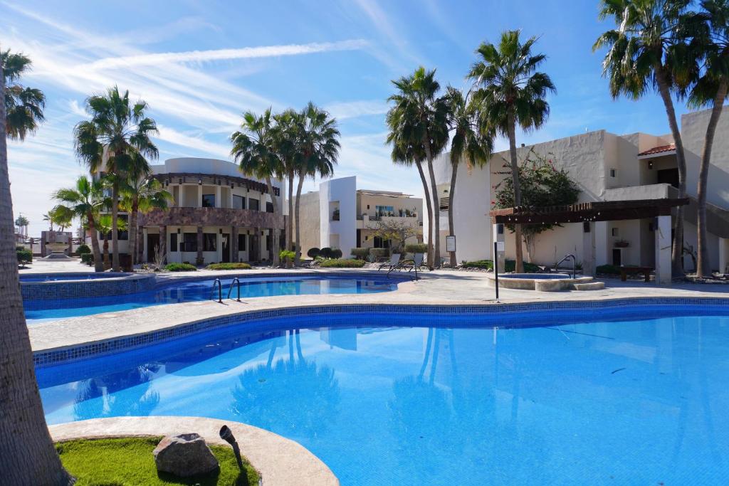 a large swimming pool with palm trees in front of a building at Beach, Please MX in Puerto Peñasco