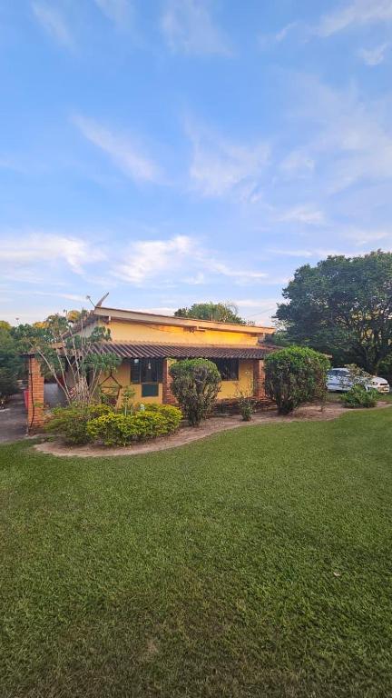 a yellow building with a grass yard in front of it at Chácara Seu Antônio in Mombuca