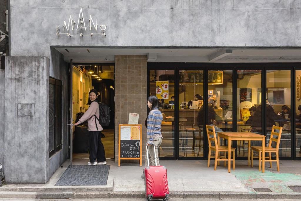 a young child standing outside of a store with a suitcase at Imano Tokyo Hostel in Tokyo