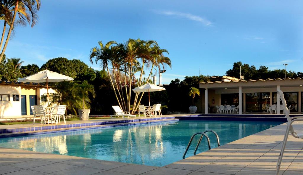 uma piscina com cadeiras e guarda-sóis ao lado de uma casa em Hotel Pousada Lord em Teixeira de Freitas