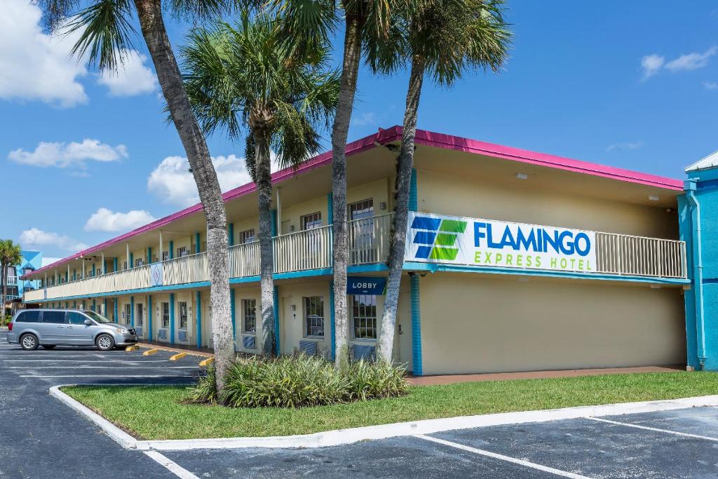 un hôtel avec des palmiers dans un parking dans l'établissement Flamingo Express Hotel, à Kissimmee