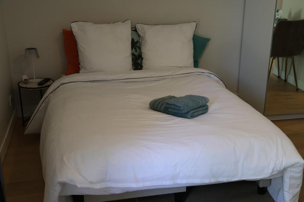 a white bed with a green towel on it at Studio for 2 people in Bouloc