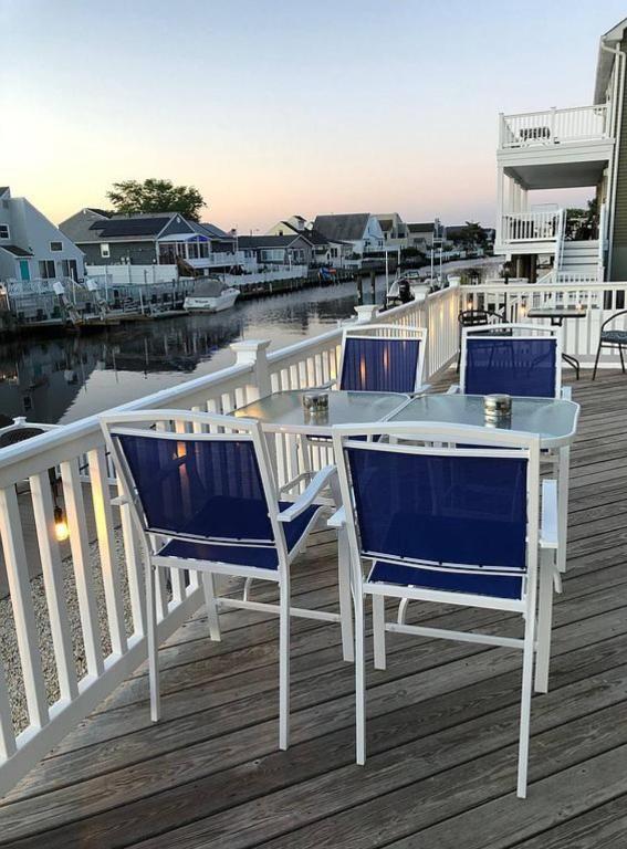 a deck with three chairs and a table on a dock at Waterfront with Heated Pool, Dock & Outdoor Fun ! in Beach Haven West