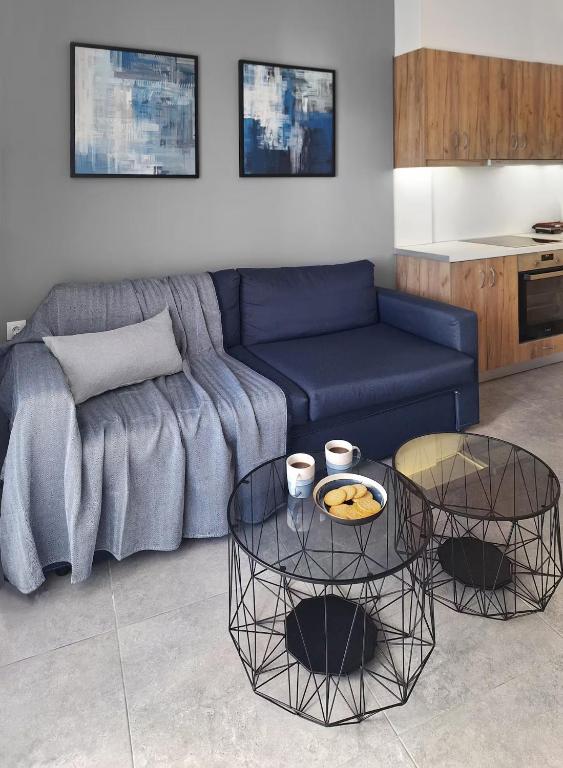 a living room with a blue couch and two tables at Blue wave in Ierapetra