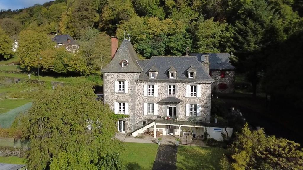 a large stone house on a hill with trees at La Demeure de Cyr in Saint-Chamant