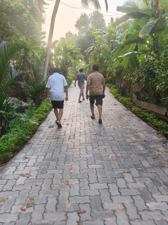 three men walking down a stone walkway at Lagoon celebration10 in Perumanseri