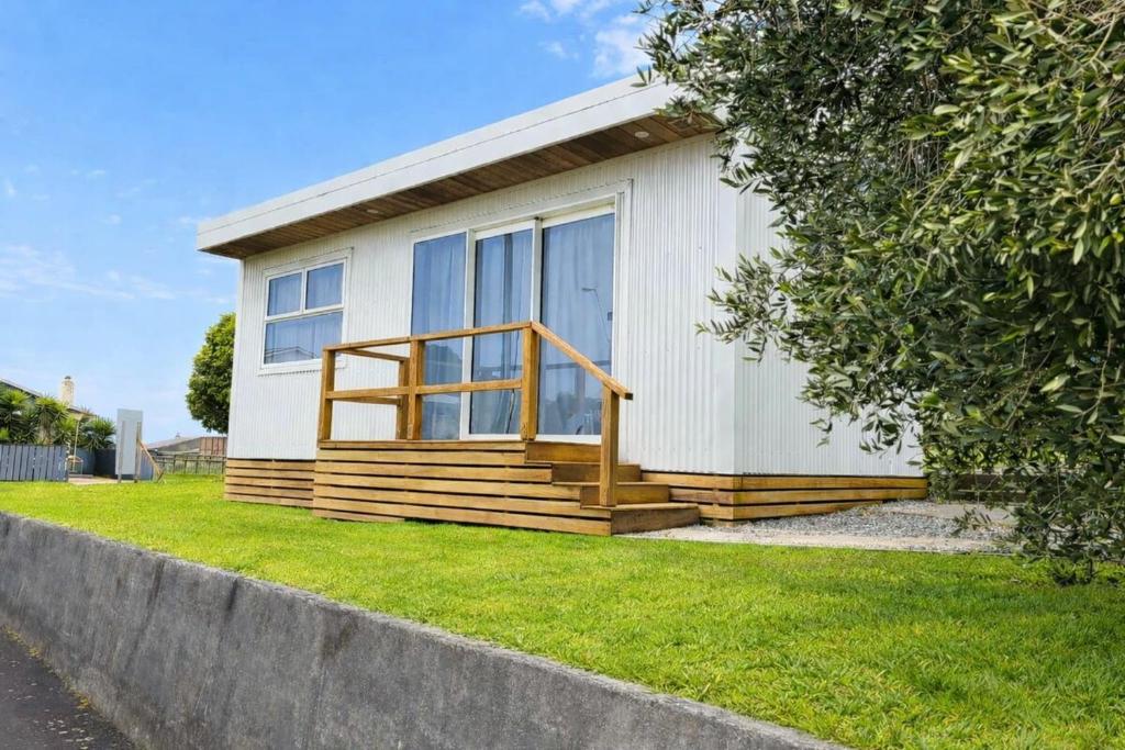 a small white house with a porch and a door at Blagdon Close Guesthouse in New Plymouth