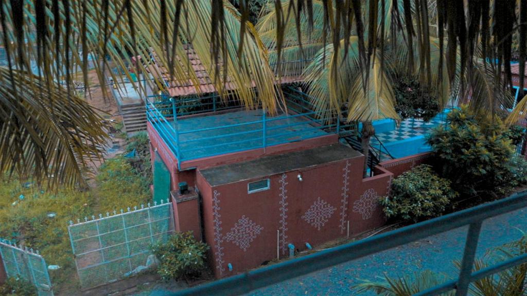 an overhead view of a house with blue stairs and palm trees at bethi farms in Malkāpur